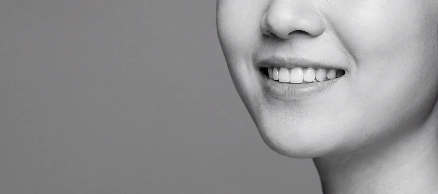 진료 안내 이미지 — 치아가 보이게 웃는 모델의 흑백 옆얼굴 (AI 생성 이미지)