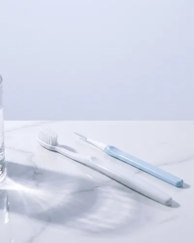 흰 대리석 위에 놓인 칫솔과 치간칫솔 (AI 생성 이미지)